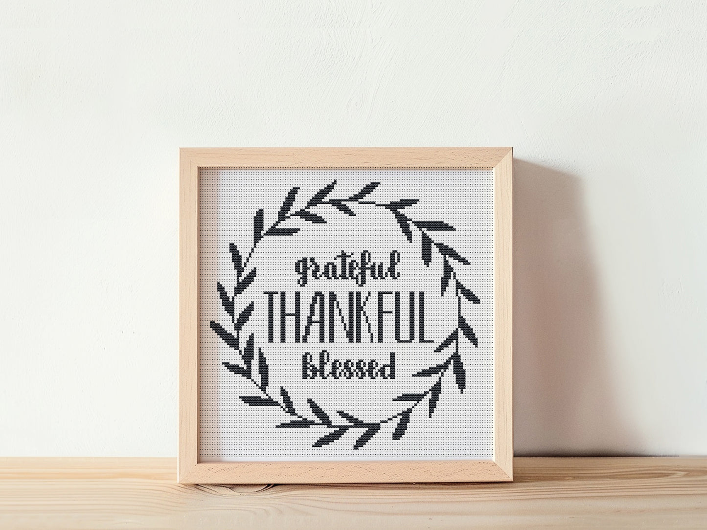Framed cross-stitched art with 'Grateful Thankful Blessed' text on a white background