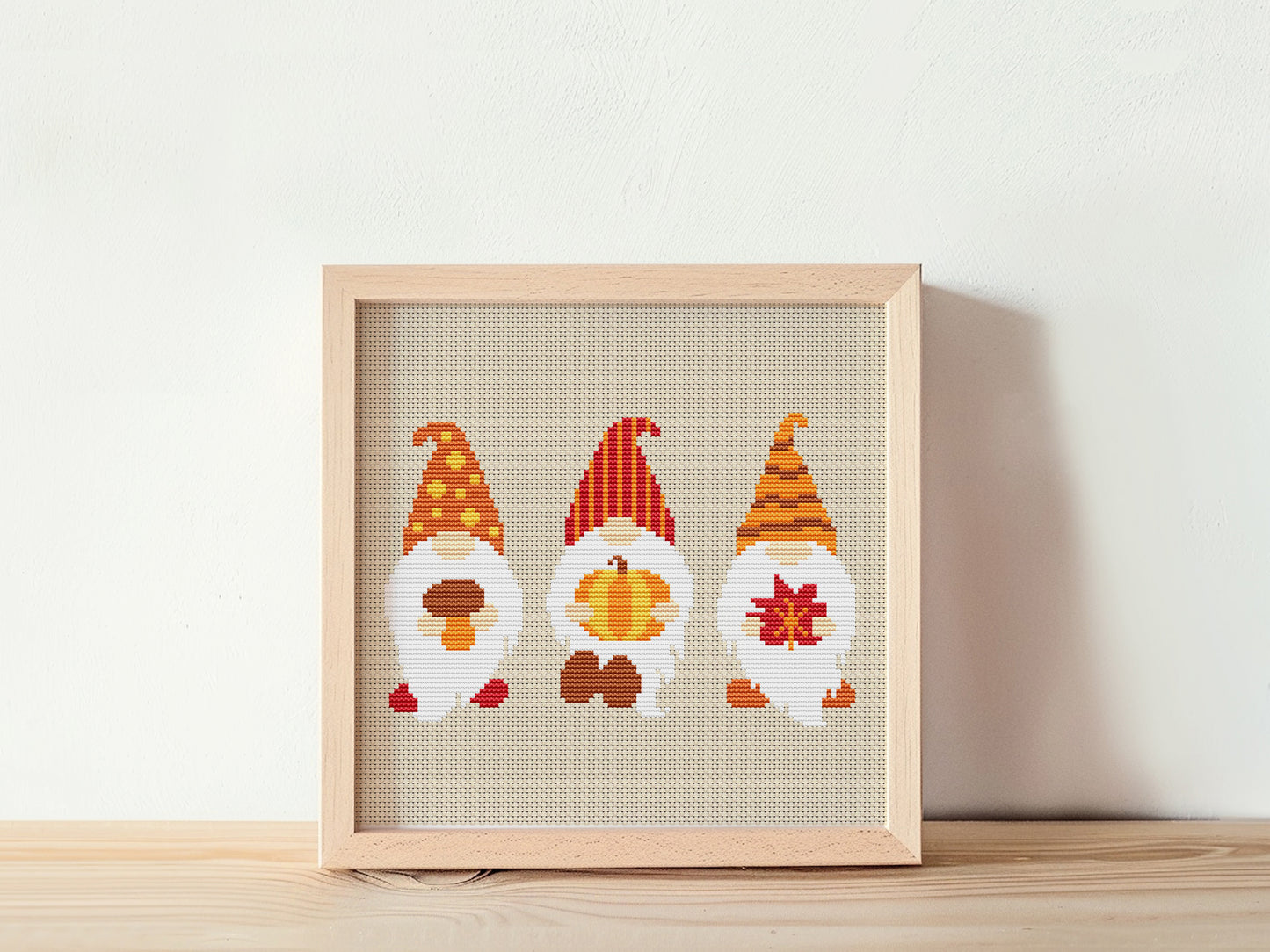 Framed cross-stitched gnomes on a white background