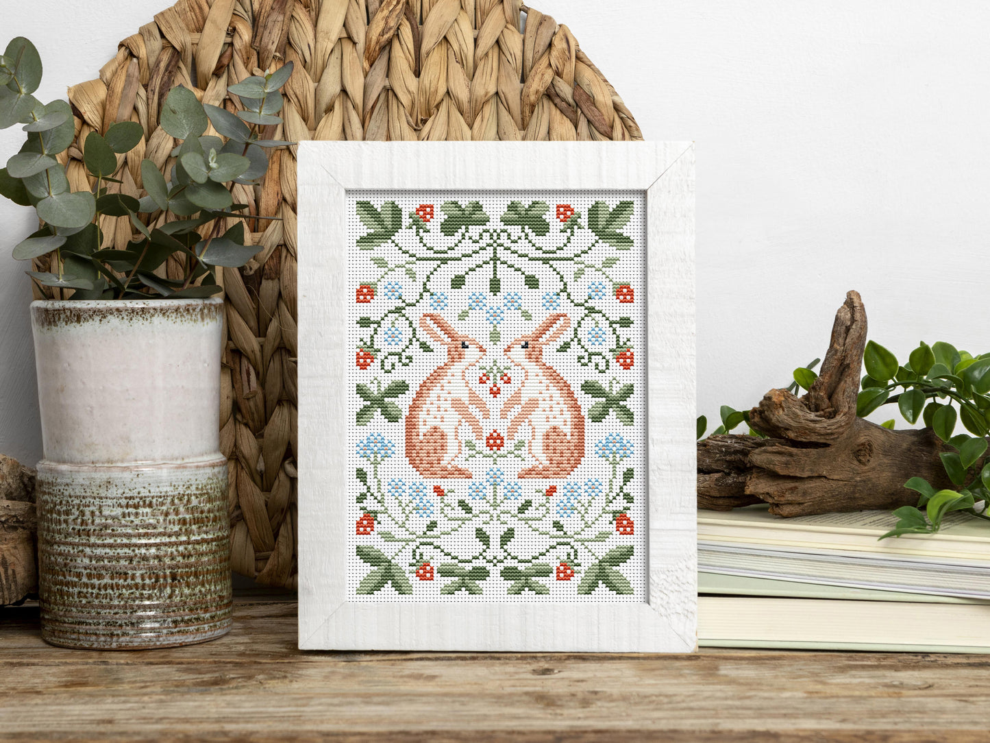 Folk cross stitch pattern with rabbits, leaves, and strawberries in woodland style