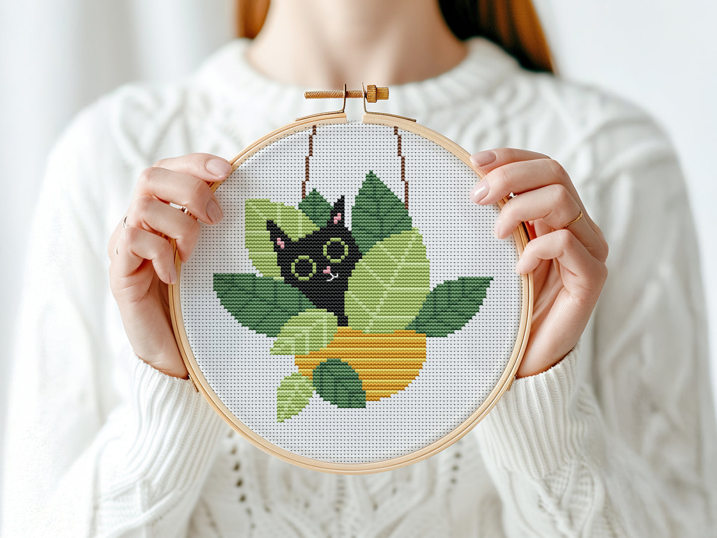 Funny cross stitch pattern with cat sitting in plant pots, playful home decor design