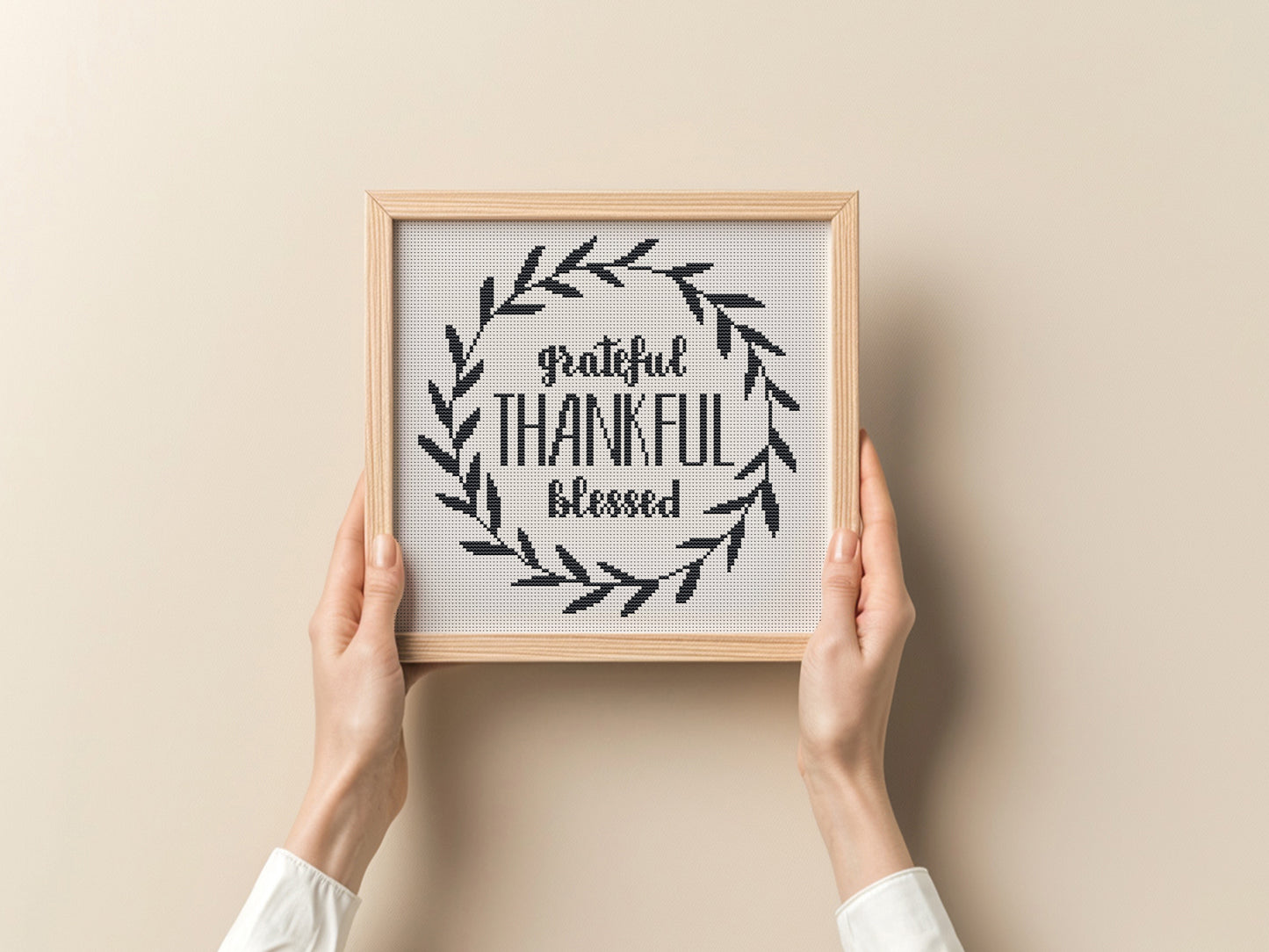 Framed print with 'grateful, thankful, blessed' text held by hands against a beige background