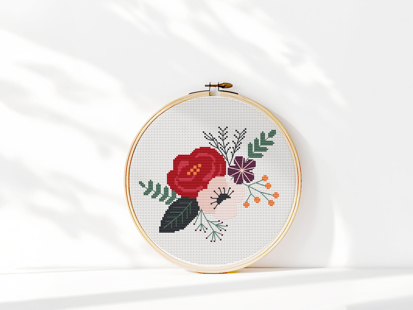 Modern burgundy floral cross stitch pattern in hoop for home decor.
