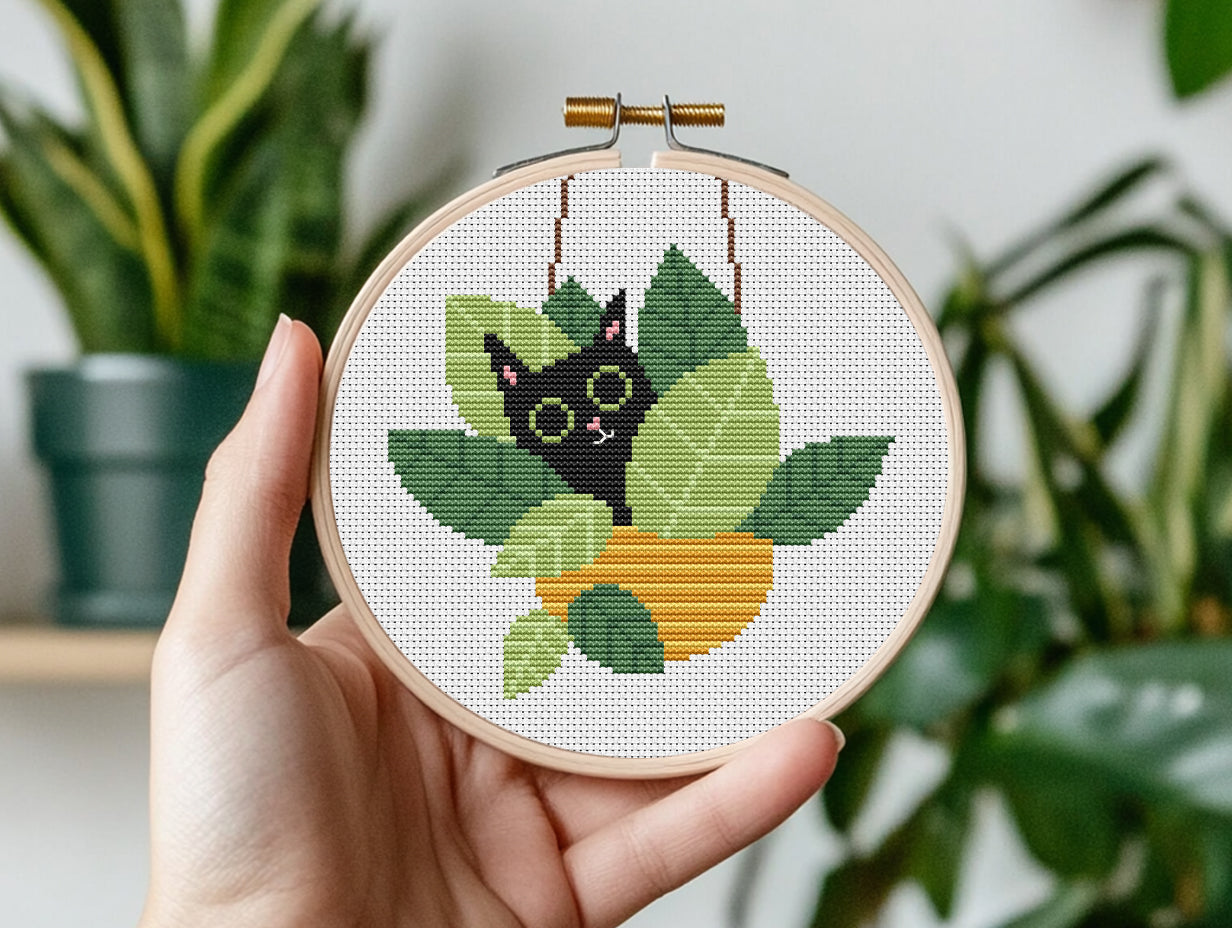 Funny cross stitch pattern with cat sitting in plant pots, playful home decor design