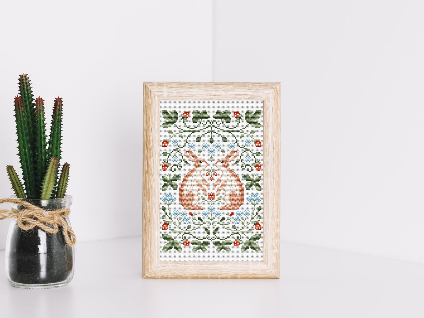 Folk cross stitch pattern with rabbits, leaves, and strawberries in woodland style
