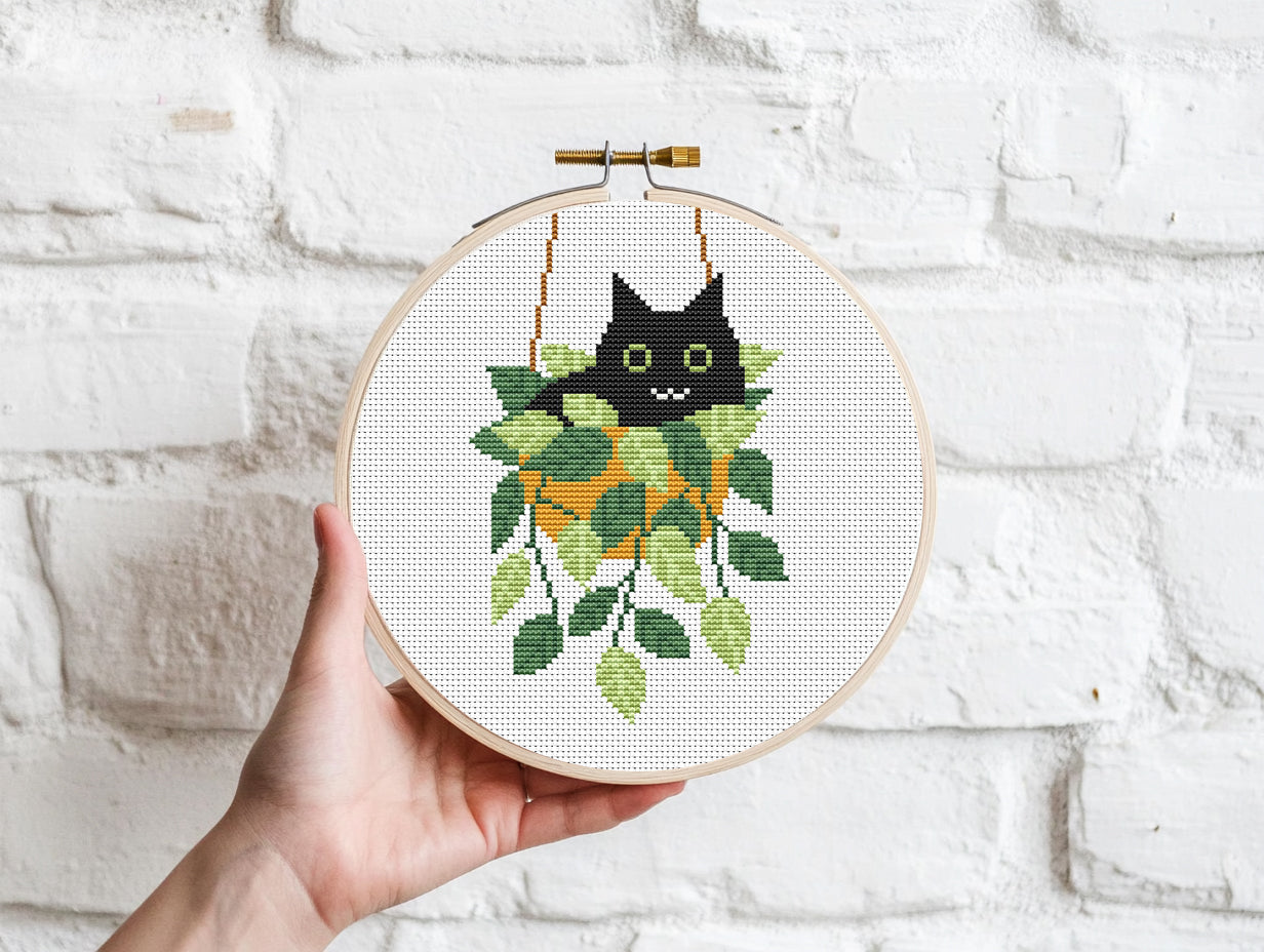 Cute relaxed cat cross stitch pattern sitting in plant pot, peaceful and cozy design
