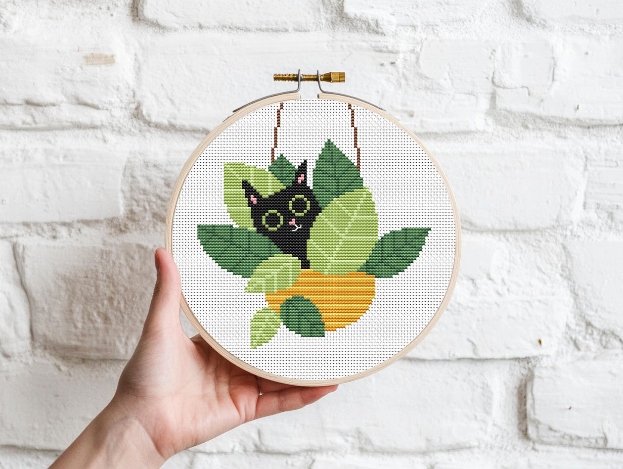 Funny cross stitch pattern with cat sitting in plant pots, playful home decor design