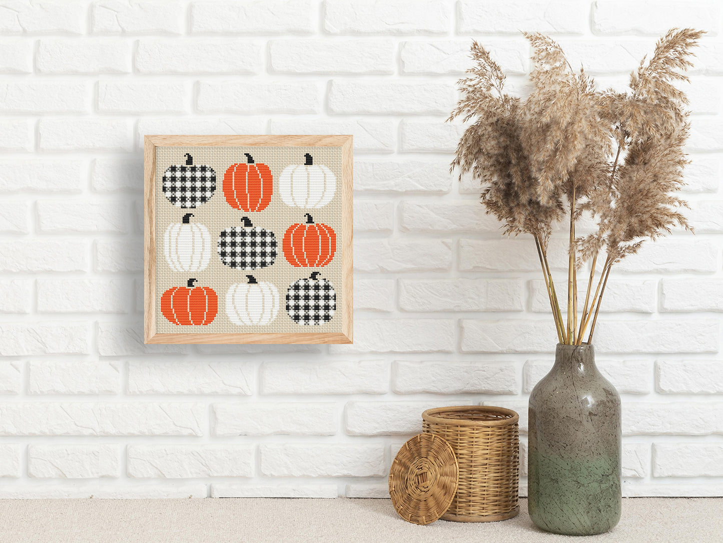 Framed artwork of pumpkins on a white brick wall with decorative items below.