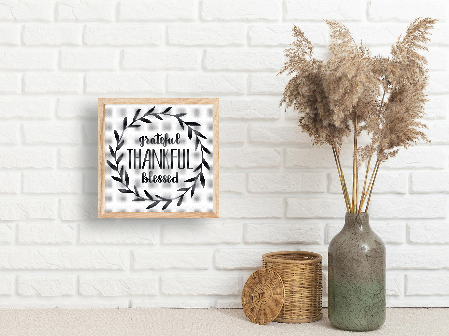 Framed artwork with 'Grateful Thankful Blessed' text on a white brick wall with decorative elements.