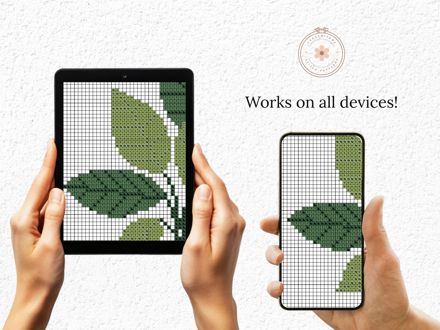 Hands holding a tablet and phone displaying cross-stitch patterns of leaves.