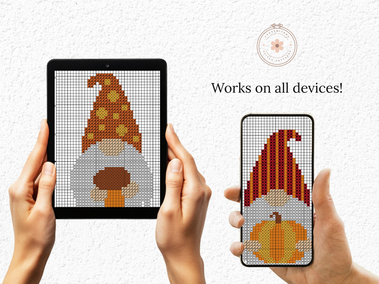 Two hands holding a tablet and phone displaying cross-stitch patterns of gnomes and pumpkins.