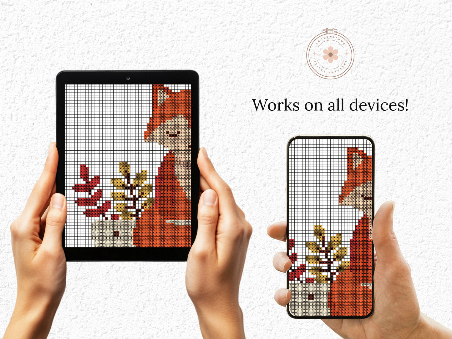 Hands holding a tablet and phone displaying a cross-stitch design of a fox and plants.