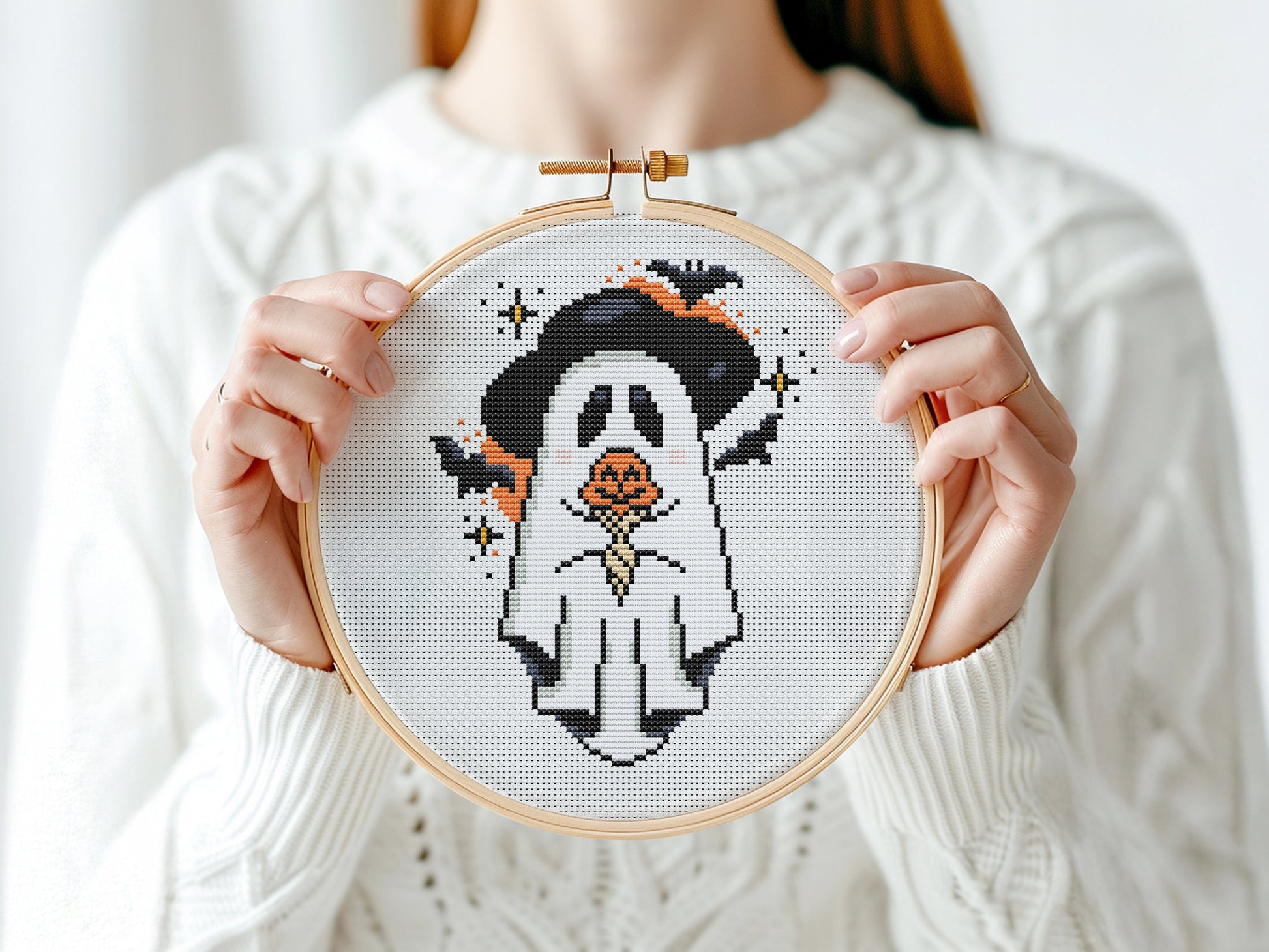 Halloween cross stitch pattern with a ghost holding a pumpkin