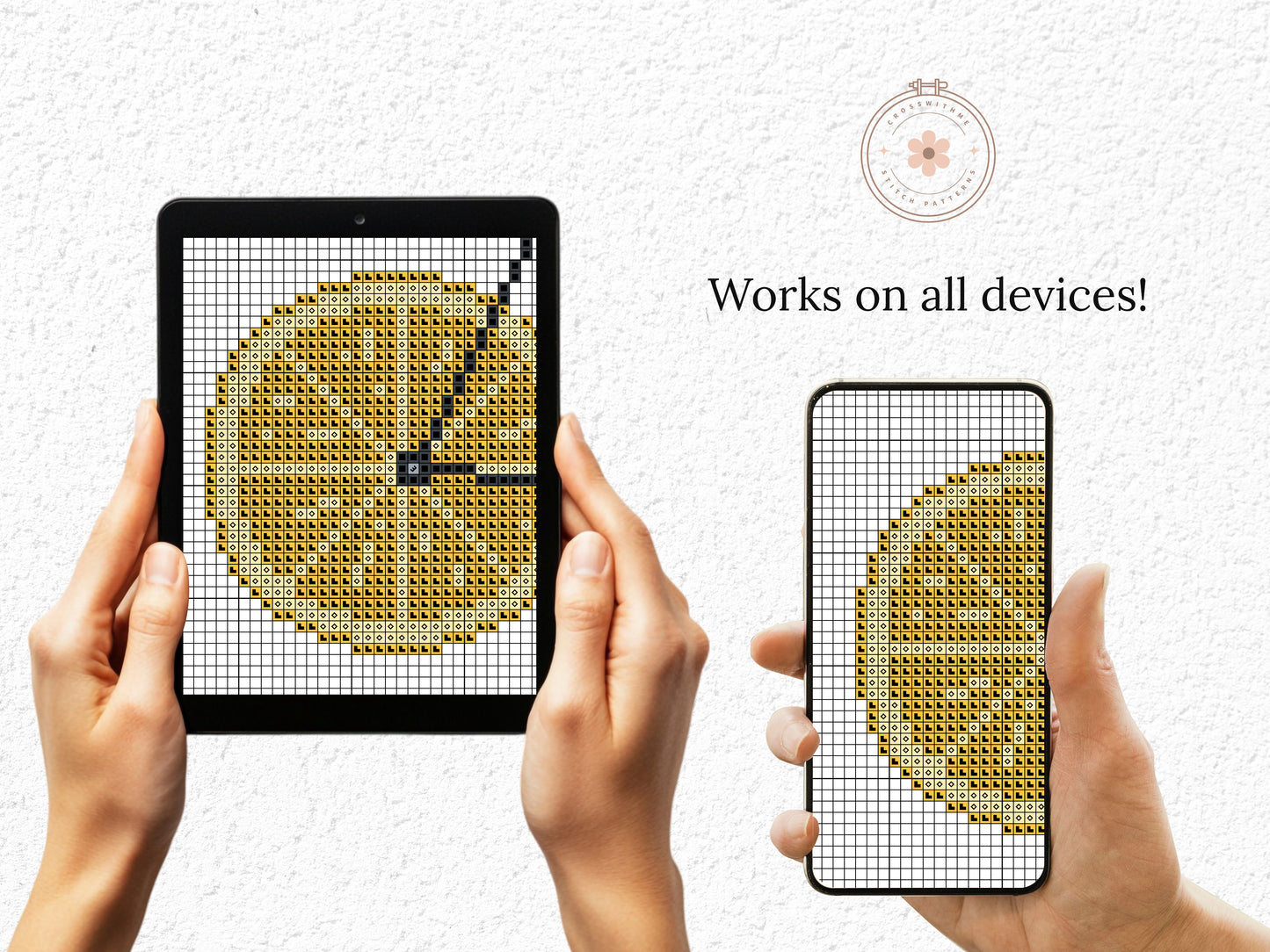 Two hands holding a tablet and phone displaying cross-stitch patterns of lemons.