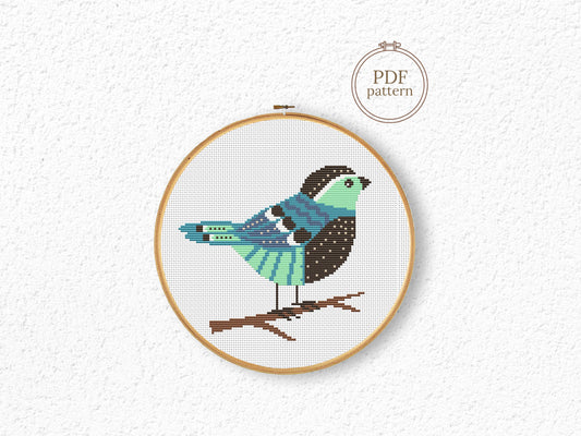 Cross-stitched bird design in a wooden hoop on a white background