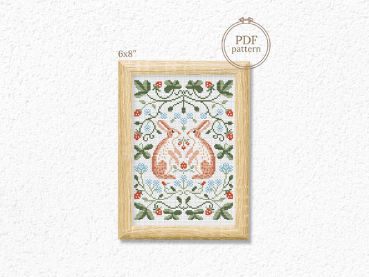 Folk cross stitch pattern with rabbits, leaves, and strawberries in woodland style