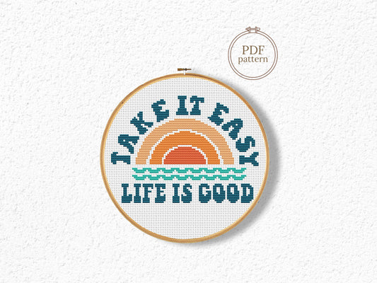 Cross-stitched hoop with 'Take it easy, life is good' text on a textured white background