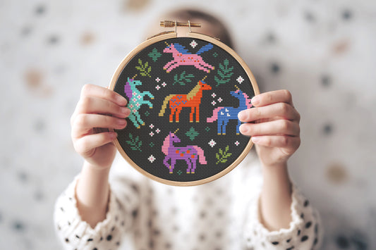 Colorful unicorns surrounded by leaves cross stitch pattern, whimsical fantasy PDF embroidery design.