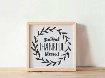 Framed cross-stitched art with 'Grateful Thankful Blessed' text on a white background