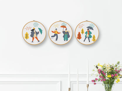 Set of three autumn cross stitch patterns with people, umbrellas, rain, and puddle