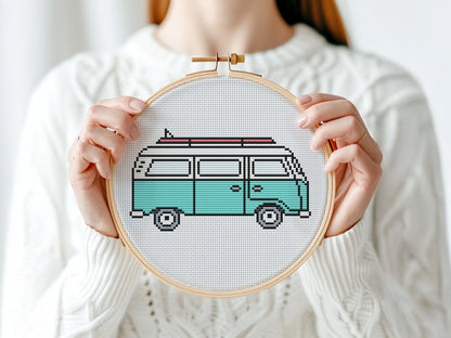 Person holding a cross-stitched design of a van in an embroidery hoop.