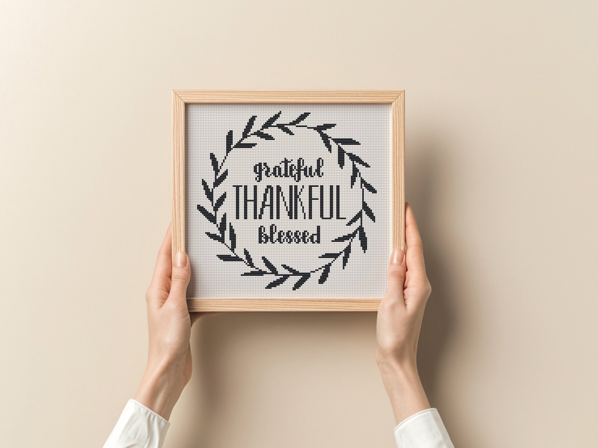 Framed print with 'grateful, thankful, blessed' text held by hands against a beige background