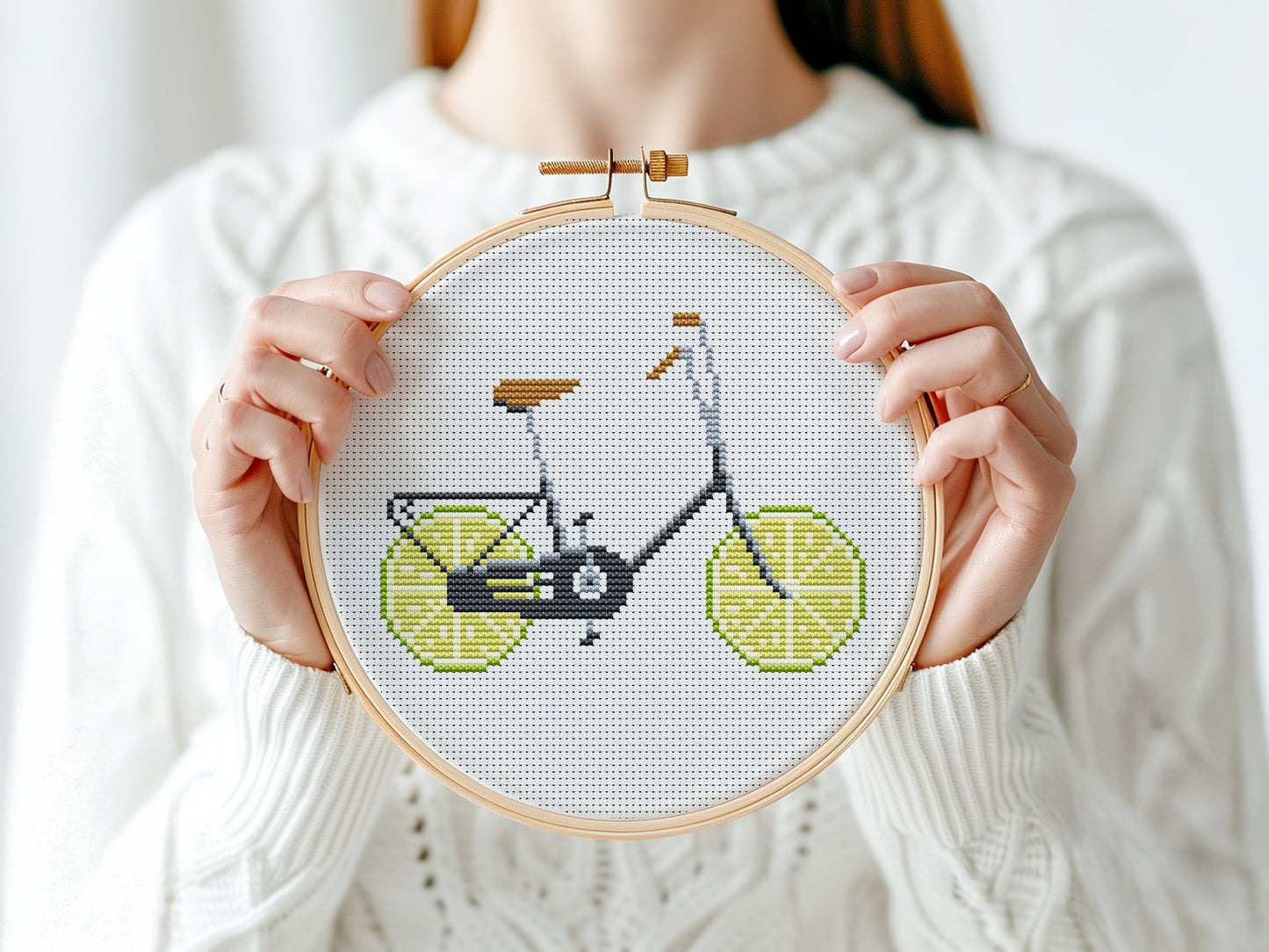 Person holding a cross-stitched bicycle with lemon wheels design.