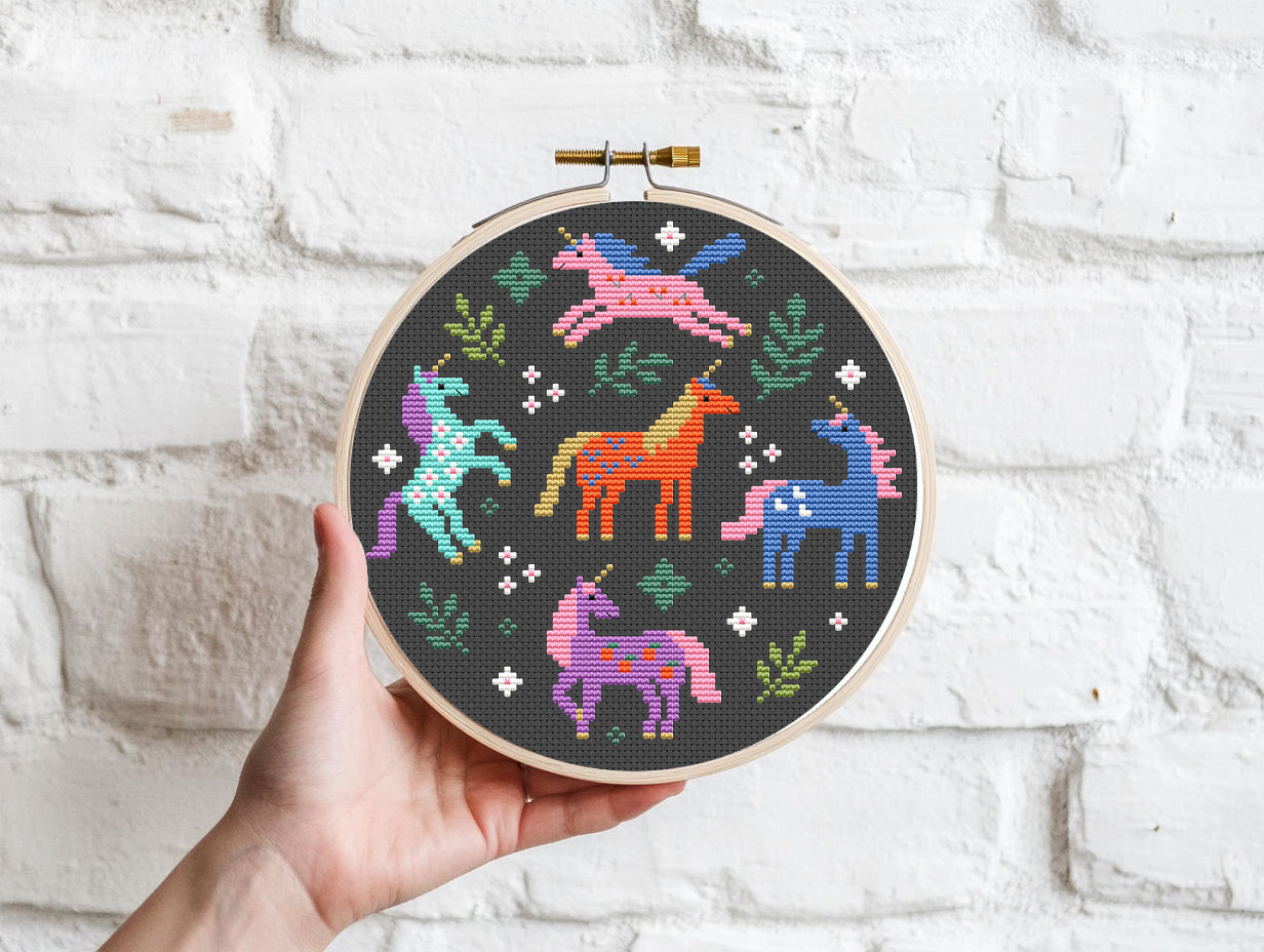 Colorful unicorns surrounded by leaves cross stitch pattern, whimsical fantasy PDF embroidery design.