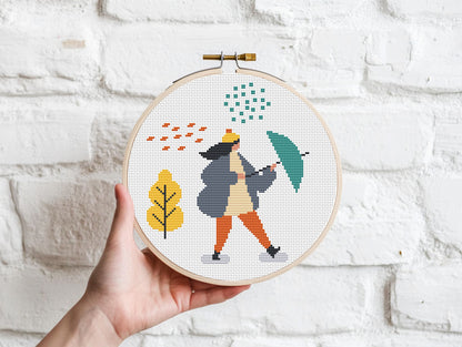 Set of three autumn cross stitch patterns with people, umbrellas, rain, and puddle